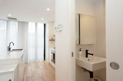W białej łazience znajduje się umywalka i lustro. w obiekcie Coastal Cool Maroubra w mieście Sydney