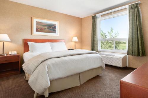 a hotel room with a large bed and a window at Days Inn & Suites by Wyndham Cochrane in Cochrane