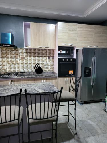 cocina con nevera, mesa y sillas en Dvyne Luxury Home en Ikeja