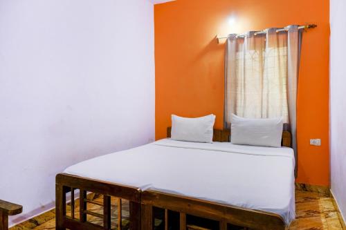 a bed in a room with an orange wall at OYO Mahamaya Holiday Inn Near Calangute Beach in Calangute