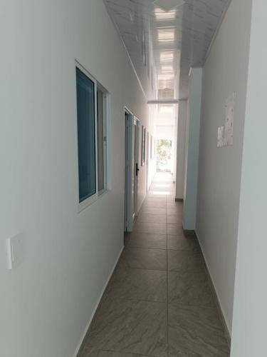 an empty hallway with white walls and a tile floor at HOSPEDAJE EL ENSUEÑO in Doradal