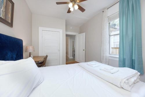 a bedroom with a white bed with a ceiling fan at The Chattahoochee Cottage Walk to River & Shops in Columbus