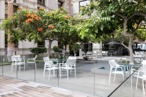 a patio with tables and white chairs and trees at Holiday Inn Express - Iquique by IHG in Iquique