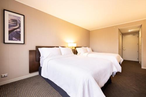two beds in a hotel room with white sheets at Holiday Inn Express - Iquique by IHG in Iquique