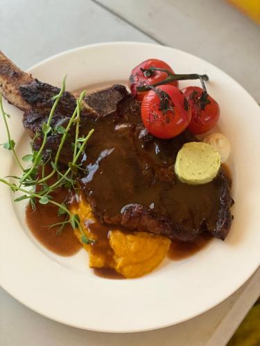 a plate of meat with sauce and tomatoes on it at Destiny Hotel in Harhorin