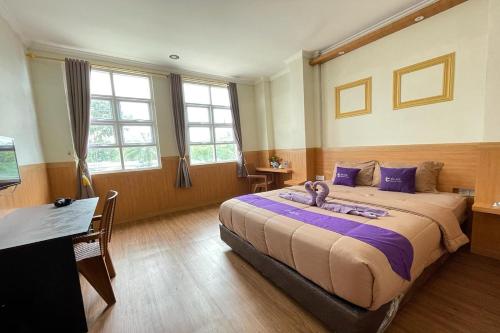 a bedroom with a large bed with purple pillows at Take Guesthouse 1 in Jambi