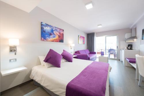 a hotel room with a large bed with purple pillows at eó Corona Cedral in Puerto Rico de Gran Canaria