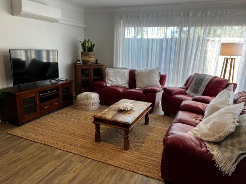 a living room with red couches and a coffee table at Eleven - Oceanside Retreat Busselton in Broadwater