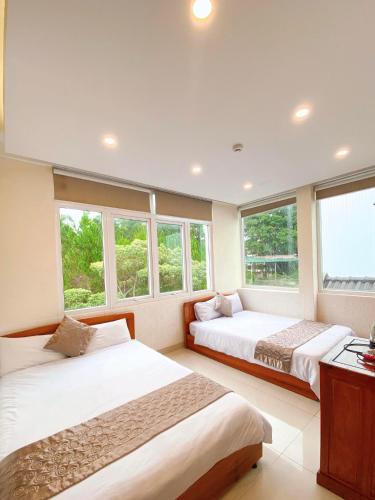 two beds in a room with windows at Hotel Phạm Duy in Da Lat