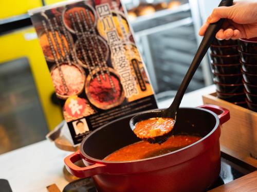 a person stirring a pot of food with a spoon at Super Hotel Premier JR Nara Eki in Nara