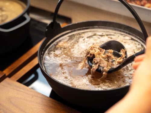 a person is stirring a pot on a stove at Super Hotel Premier JR Nara Eki in Nara