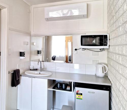 una pequeña cocina blanca con fregadero y microondas en Motel Yarrawonga, en Yarrawonga