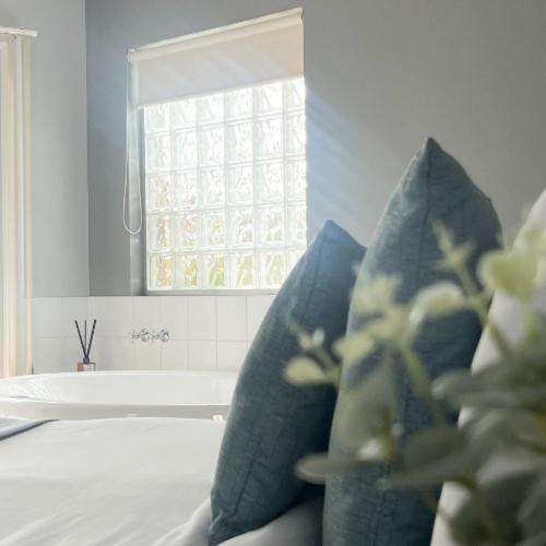 Habitación con almohadas azules, ventana y bañera. en Waves Luxury Suites, en Port Campbell