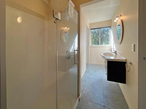 y baño con ducha acristalada y lavamanos. en Oneroa Village Beach House- Waiheke Escapes, en Oneroa