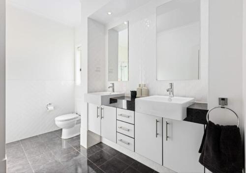 a white bathroom with two sinks and a toilet at Premium Barossa Getaway in Tanunda