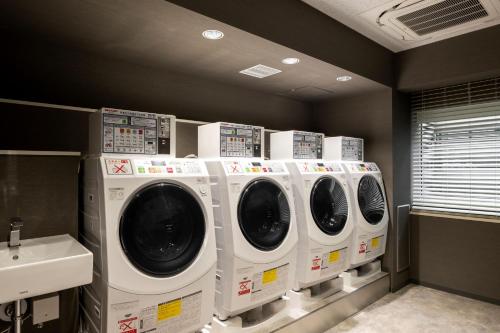 a row of washers and dryers in a laundry room at remm Akihabara in Tokyo