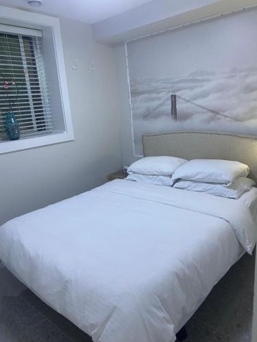 1 cama blanca grande en un dormitorio con ventana en Panorama VistaVue Vancouver en Vancouver