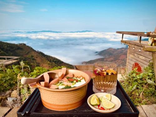 a table topped with a bowl of food and a drink at Tà Xùa Haus Meej Homestay in Bắc Yên