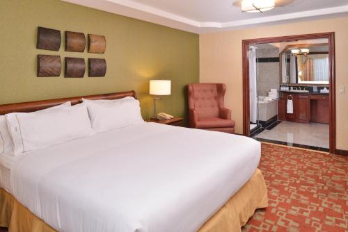 a bedroom with a large white bed and a chair at Holiday Inn Express Hotel & Suites El Centro by IHG in El Centro
