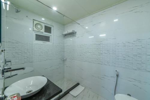 a white bathroom with a sink and a toilet at Hotel Anmol Bandhan in Jaipur