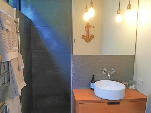 uma casa de banho com um lavatório e um chuveiro em Wave Song - Waiheke Escapes em Onetangi