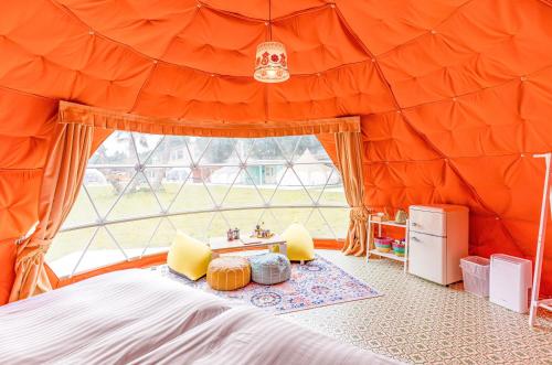 香取にあるTACO GLAMPのベッドルーム1室(オレンジ色のテント、ベッド1台、窓付)