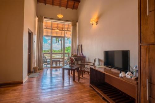 a living room with a flat screen tv and a table at Lavendish Wild Wilpattu in Nochchiyagama