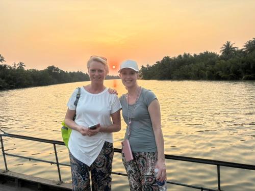 two women standing on a boat on the water at Bentre Coco Lodge in Ben Tre