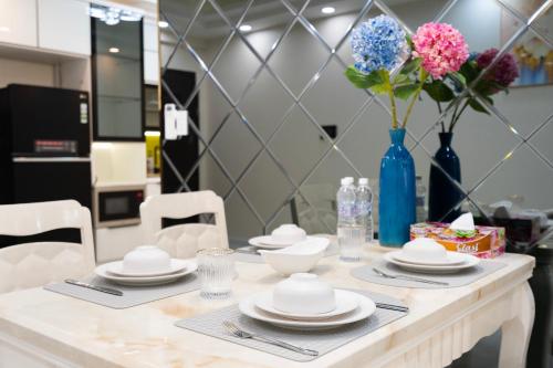 einen Tisch mit weißen Gerichten und eine blaue Vase mit Blumen in der Unterkunft Three Bedroom Scenic Valley in Ho-Chi-Minh-Stadt