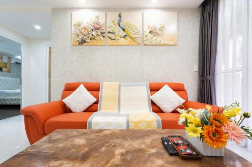 ein Wohnzimmer mit einem orangenen Sofa und Blumen in der Unterkunft Three Bedroom Scenic Valley in Ho-Chi-Minh-Stadt