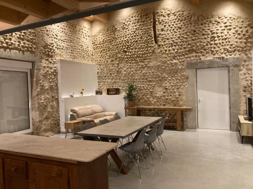 une salle à manger avec une table et des chaises et un mur en pierre dans l'établissement Les vieilles pierres drômoises, à Alixan