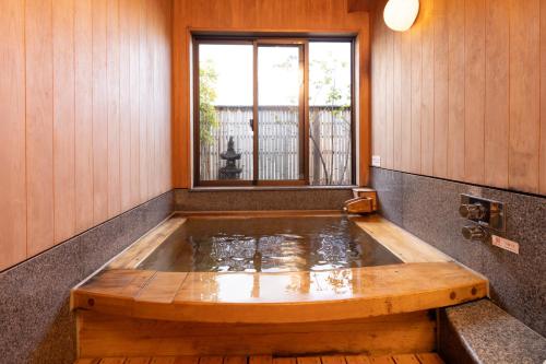 uma banheira de hidromassagem num quarto com janela em Ryokan Asakusa Shigetsu em Tóquio