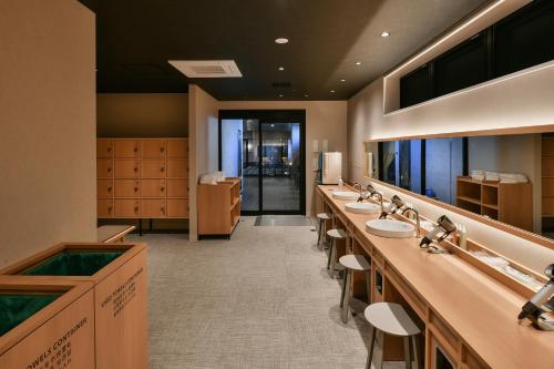 a bathroom with a row of sinks and mirrors at REF Matsuyama City Station by VESSEL HOTELS in Matsuyama