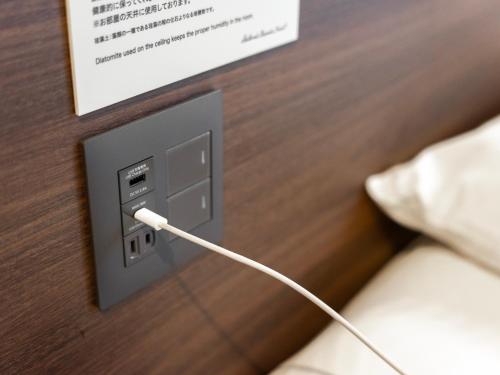 a white cord plugged into a electrical outlet on a bed at Super Hotel Premier JR Nara Eki in Nara