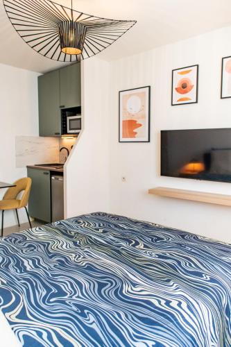 Cet appartement comprend une chambre avec un lit bleu et blanc et une cuisine. dans l'établissement Villeurbanne Centre Appartement Meublé, à Villeurbanne