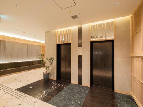 a lobby with two elevators and a potted plant at Super Hotel Premier JR Nara Eki in Nara