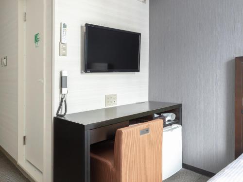 a room with a desk with a television on a wall at Vessel Inn Hiroshima Station in Hiroshima
