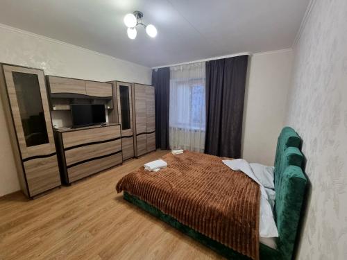 een slaapkamer met een bed, een bank en een televisie bij Port City apartment in Loetsk