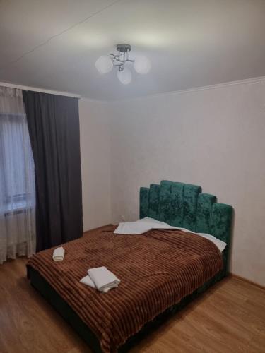een slaapkamer met een groot bed met een groen hoofdeinde bij Port City apartment in Loetsk