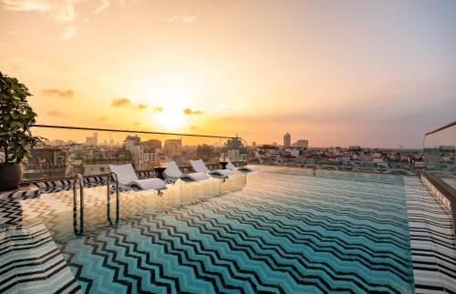 a pool on the roof of a building with a sunset at CLASSYC Hotel in Hanoi