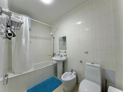 a white bathroom with a toilet and a sink at Raduga West 'Emerald' Cottage in Koshkolʼ