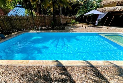a large blue swimming pool next to a wooden fence at Lujosa Mansión Tipo Bali in Melgar