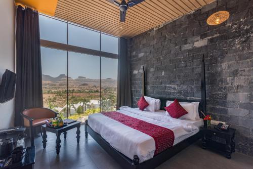 ein Schlafzimmer mit einem großen Bett und einem großen Fenster in der Unterkunft Wabi Sabi Resort, Igatpuri in Wādhiware