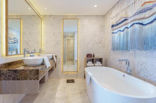 a bathroom with a tub and a sink at Golden Tulip Springhill Lampung in Bandar Lampung