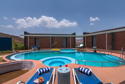 a swimming pool with chairs and a building at Wabi Sabi Resort, Igatpuri in Igatpuri