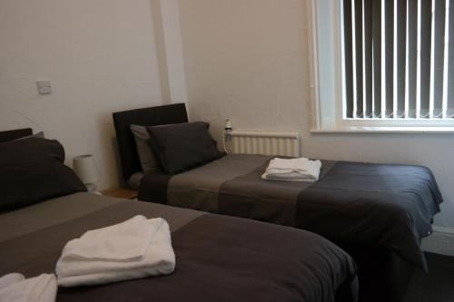 a room with two beds and a couch and a window at Cardoh Lodge in Blackpool