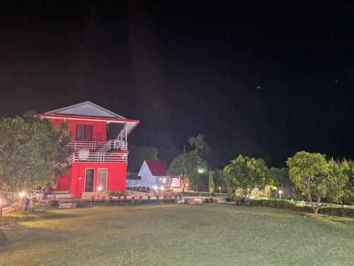 a red house at night with a large yard at Kanva Farms in Kotdwāra