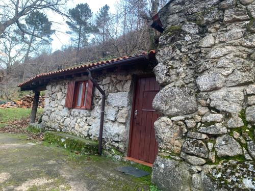 a stone house with a red door in a stone wall at Chalé na Montanha - Casa de Cima in Manteigas