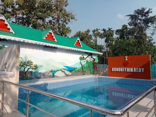 uma piscina num resort com uma placa em Bonobithikaloy Resort & Restaurant em Chālsa Mahābāri