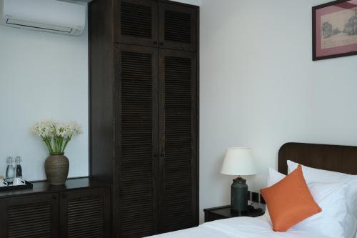 a bedroom with a bed and a wooden closet at Paul Chabot Hotel in Hai Phong